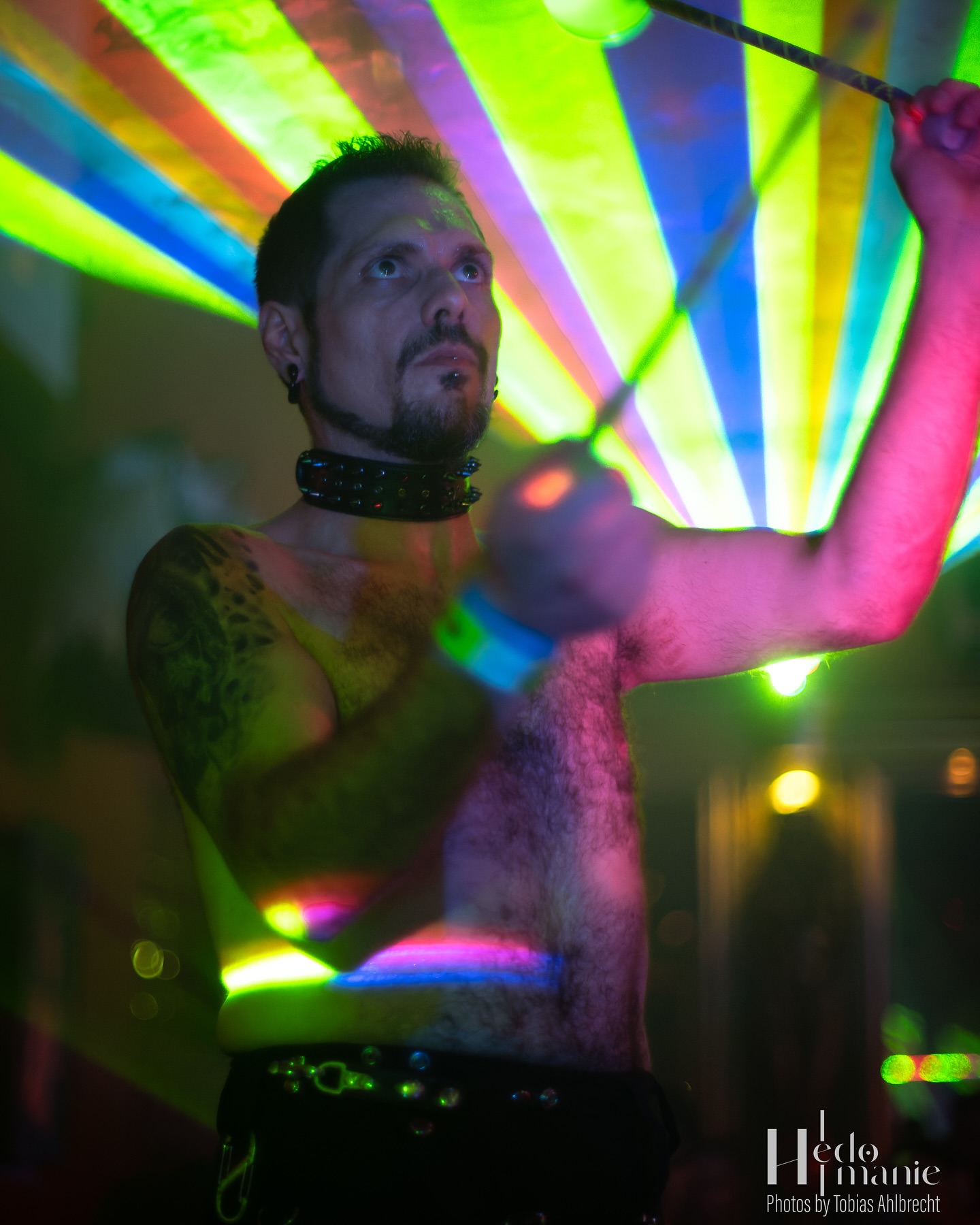Fabiano performing poi beneath rainbow-coloured lasers at Insomnia